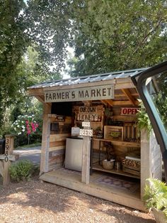 a car parked in front of a small wooden market stand with an open door on the side