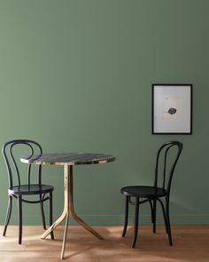 two chairs sitting at a table in front of a wall with green paint on it