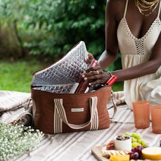 a woman sitting at a table with a brown bag on top of it and some drinks