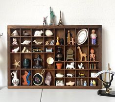 a wooden shelf filled with figurines and other items on top of a table