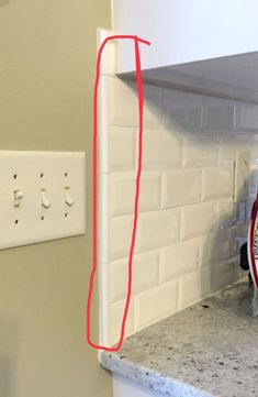 a kitchen counter with a clock on the wall next to it and a red marker pointing up