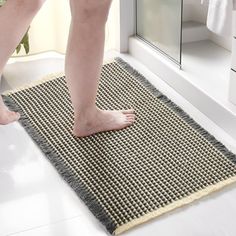 a person standing on a bathroom rug in front of a shower