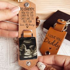 a person holding a keychain with an image of a baby on it and the words i love you daddy