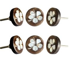 four wooden knobs with white flowers on them and one is turned to the side