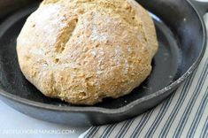 a loaf of bread in a skillet on top of a table with blue and white napkins