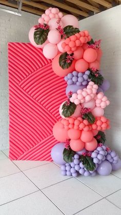 a tall pink and purple balloon sculpture on the floor in front of a brick wall