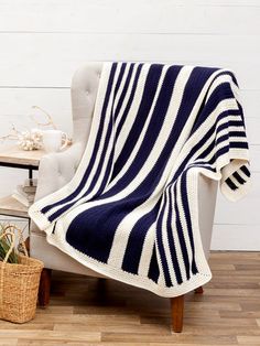 a blue and white striped blanket sitting on top of a chair next to a potted plant