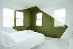 a bedroom with green walls and white bedding in the corner, along with two windows