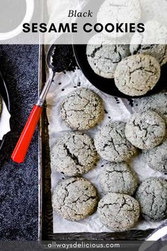 black sesame cookies on a tray with red handled utensils and spoons next to them