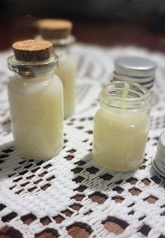 two jars filled with liquid sitting on top of a doily next to silver containers