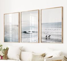 three framed pictures hang on the wall above a couch in a living room with white furniture