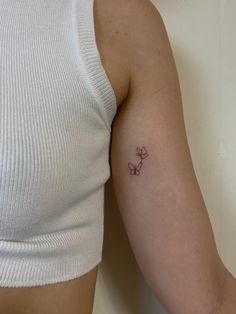 a woman's arm with a small flower tattoo on the left side of her arm