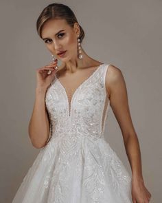 a woman in a wedding dress posing for the camera with her hand on her cheek