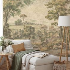 a living room with a white couch and wallpaper that has trees painted on it