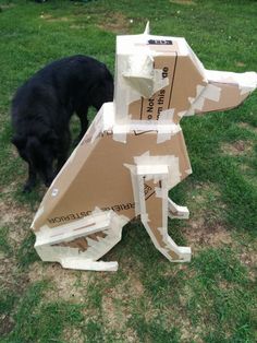 a black dog standing next to a cardboard sculpture