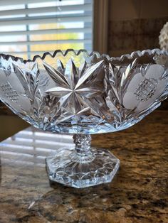 a crystal bowl sitting on top of a counter next to a window with blinds in it