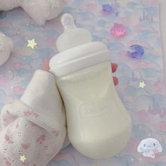 a person holding a baby bottle in their hand on a surface with stars and confetti