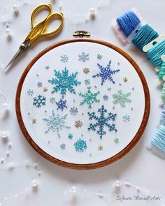 an embroidery kit with snowflakes on it next to scissors and thread spools