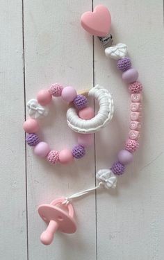 a pink and white beaded pacifier next to a hook