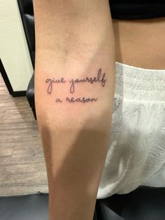 a woman's arm with the words give yourself a reason tattooed on her forearm