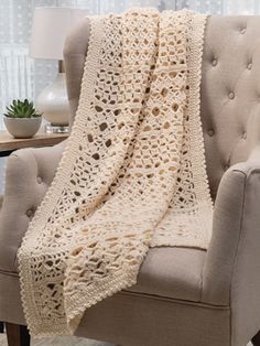 a white crocheted blanket sitting on top of a chair