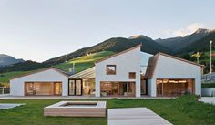 a white house sitting in the middle of a lush green field with mountains behind it