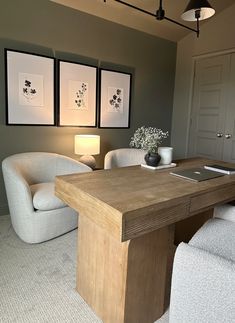 a room with two chairs, a desk and three pictures on the wall above it