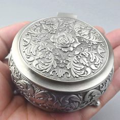 a person is holding a small silver box in their hand and it looks like they have been made out of metal