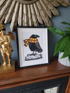 a gold statue is sitting next to a framed art print on a shelf in front of a decorative sunburst