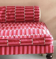 a red and white striped couch sitting on top of a hard wood floor next to a wall