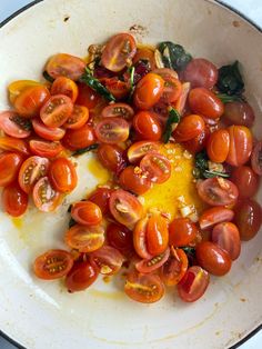 tomatoes and spinach are being cooked in a pan on the stove top with oil