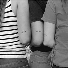 three girls with small tattoos on their arms, one has the word love and the other has