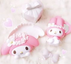 two pink hello kitty erasers sitting on top of a white surface next to hearts