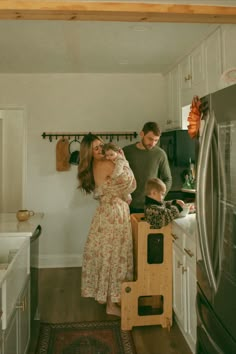 a man and woman standing in a kitchen with a toddler on the counter next to them