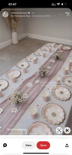 the table is set up with pink and white plates, cups and flowers on it