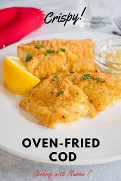 a white plate topped with fried fish next to a lemon wedge