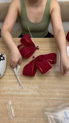 a woman is cutting ribbon with scissors on a wooden table in front of a christmas ornament