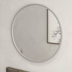 a round mirror hanging on the wall next to a coat rack