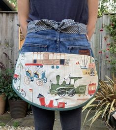 a woman is holding an apron made out of old jeans and other things in the back