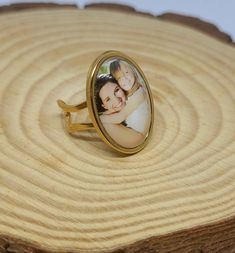 a ring with an image of two people on it sitting on top of a piece of wood