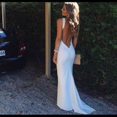 a woman in a white dress standing next to a car