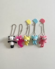 four keychains with different colors and designs on them, one is shaped like a teddy bear