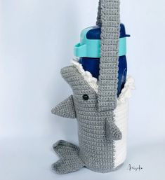 a crocheted elephant holding a water bottle in it's trunk with its mouth open