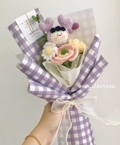 a hand holding a bouquet of flowers with a stuffed animal in it's center