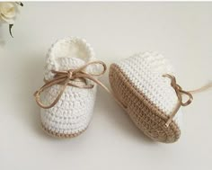 two white crocheted baby shoes tied to each other with a flower in the background