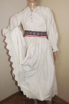 "Very old folk costume consisting of two pieces: skirt and folk shirt. Both are handmade and have handmade embroidery. The shirt is with embroidery on the shoulders, typical of the Arad region. It has fine embroidery on the sleeve, shoulders and cuffs made of beige thread. The neck has blue stitches. The shirt has old blue glass buttons. The cuffs end with laces. Fits S-M measures. Although I added more cloth under the arm to make it wider and more comfortable to wear, the shirt still has a smal Traditional White Costume Dress, Traditional Embroidered Peasant Dress, Traditional Cotton Costume Dress, White Peasant Dress For Daywear, White Cotton Peasant Prairie Dress, Peasant Outfit, Fine Embroidery, Handmade Costumes, Handmade Embroidery