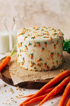 carrot cake with white frosting and sprinkles next to fresh carrots