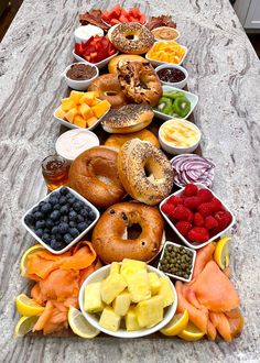 a long table topped with lots of different types of fruits and donuts on top of each other