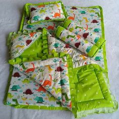 a green and white baby bedding set with dinosaurs on it