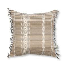 a tan and white striped pillow with fringes on the edges, in front of a white background